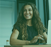 Photo of a woman smiling for a photo in front of a laptop