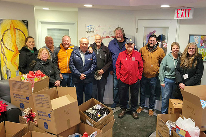 Rotary Club team photo in front of donation boxes for Christmas Hamper